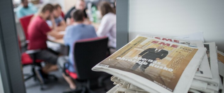 Newsroom of SME, people sitting in the room, newspapers stacked on the side